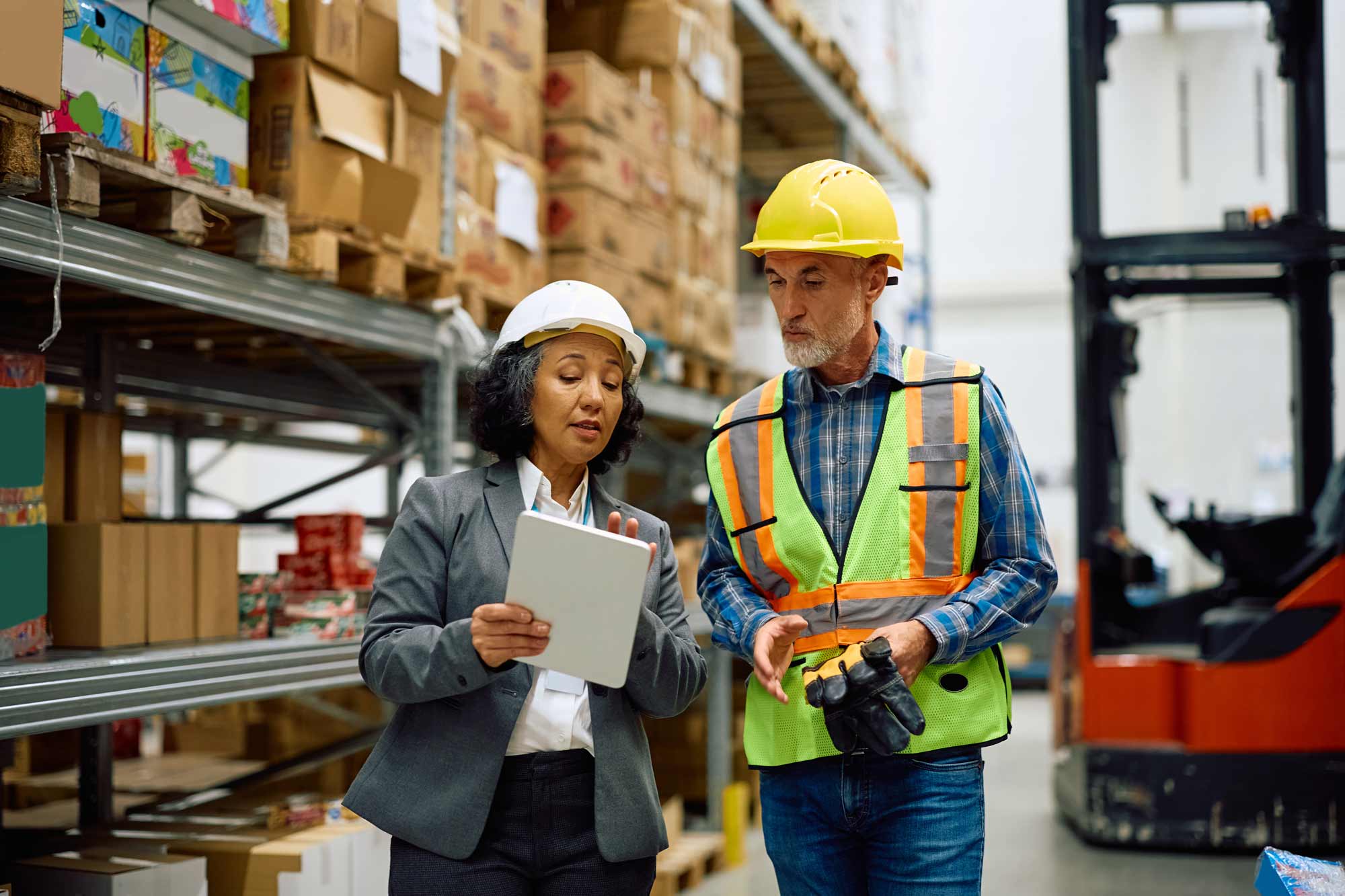 man-woman-hard-hats-discussing-warehouse